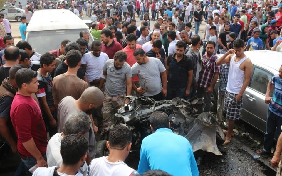 Mourners examine a cemetery car bomb wreckage