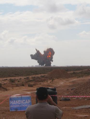 A cameraman films the explosion of 25 tonnes of ammunition (Photo: Handicap International)