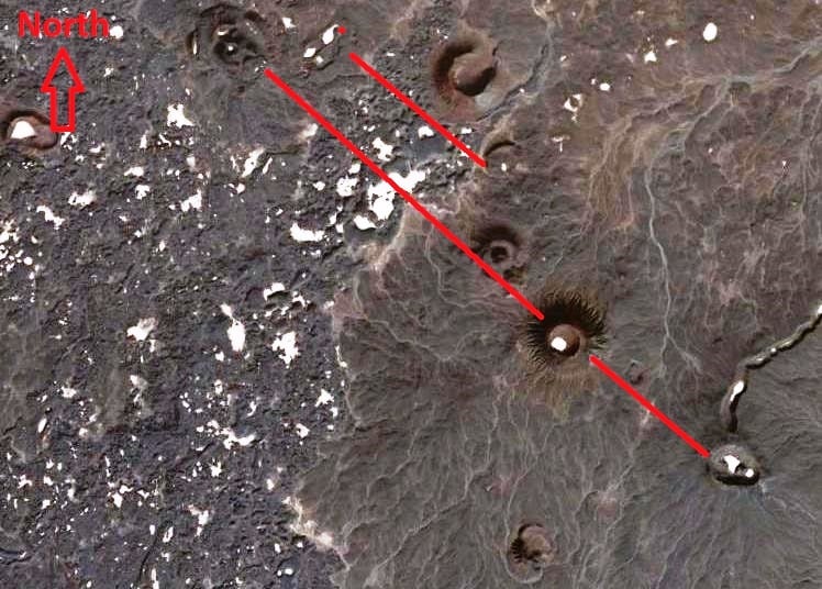 Figure 7: Satellite image showing a few volcanic cones (forming a NW-SE alignment) in central Al-Haruj Al-Aswad. These volcanoes are controlled by larger Afro-Arabian NW-SE rift system (red lines). Note the many depressions (baltas), in white color due to fine sediments in these depressions.