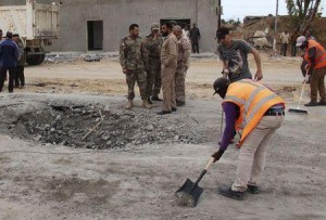 Workers clean the ground after a suicide car bomber blew himself up at a checkpoint in Dafniya outside Mistrata
