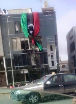 A forlorn flag hangs from the wrecked front of Nabaa TV this morning (Photo: social media)